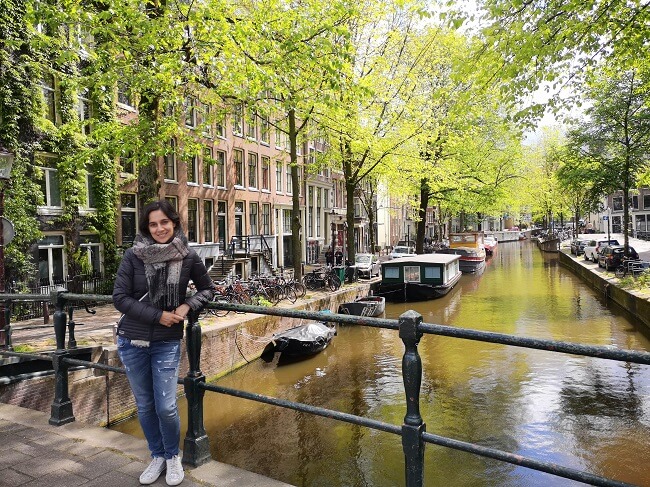 Me along Amsterdam canals in spring with short winter jacket and big scarf 